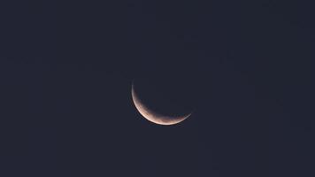 Timelapse of a thin, crescent moon gracefully moving across a clear blue sky. Serene and minimalistic celestial scene, perfect for themes of nature, astronomy, time, and tranquility video