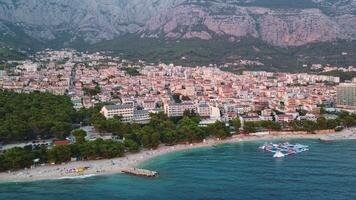 Aerial shot of Makarska city in Croatia. Coastal city with beach and houses towards the mountain. Dalmatian tourist spot video