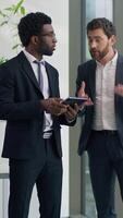 Two multiracial businessmen emotional discussing startup in office holding at digital tablet business men diverse male colleagues talking cooperation teamwork corporate friendship sharing news ideas video