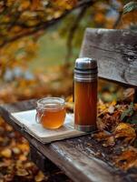 Enjoying Herbal Tea and Honey on a Forest Bench Surrounded by Autumn Leaves in a Serene Outdoor Setting photo