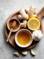 Flat Lay of Natural Cold Remedies Featuring Honey, Ginger, Garlic, and Lemon Arranged on a Wooden Board photo