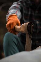 Close-Up of Ax Blade Held By Man In Plaid Shirt And Orange Gloves. photo