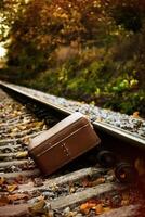 Abandoned Old Suitcase On Railroad Tracks At Sunset. photo