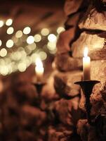 Lit Candles on Stone Wall with Bokeh Lights. A warm and inviting scene featuring flickering candlelight against a rustic stone background. photo