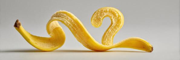 Curled Banana Peel Forms a Question Mark Shape in a Humorous Display Against a Minimalistic Backdrop photo