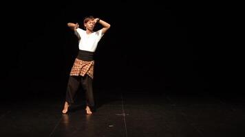 A dancer performing on stage in a traditional outfit, showcasing graceful movements against a dark background. video
