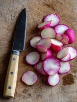 Freshly Sliced Radish on Wooden Cutting Board With Knife Ready for Culinary Preparation in a Kitchen Setting photo