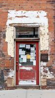 A captivating study of a weathered red door on a historic brick building, showcasing peeling paint and urban decay, a timeless architectural facade. photo