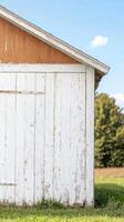 Rustic Charm Weathered White Wood Barn Wall Against Blue Sky, Capturing Timeless Rural Beauty and Textured Farmhouse Aesthetic in Sunlight photo