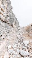 Majestic Rocky Mountain Slope A Rugged Alpine Landscape with Light-Toned Boulders and a Vast, Overcast Sky photo