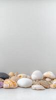 A serene arrangement of natural seashells and smooth pebbles on a light background, evoking peaceful beach memories and coastal tranquility. photo