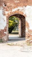 Ancient Brick Archway Ruin A Weathered Historic Passage Revealing Nature's Embrace Through Crumbling Walls and Verdant Foliage photo