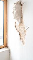 Captivating Plaster Face Sculpture Emerging from a Textured Wall, a Unique Architectural Art Installation Exploring Human Form and Space. photo