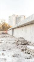 Urban construction site featuring a robust concrete wall and textured dirt foreground, highlighting modern building development and raw industrial materials. photo