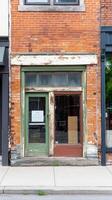 Historic brick building facade with a weathered green door and peeling paint, showcasing urban decay and vintage charm on a city street storefront. photo