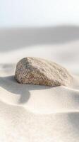 Close-up of a weathered stone on soft, golden sand, bathed in natural light, evoking tranquility and the raw beauty of coastal landscapes. photo