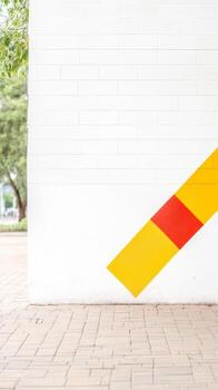 Vibrant Yellow and Red Diagonal Stripe on White Brick Wall. Modern Urban Architecture with Bold Geometric Design and Clean Lines. photo