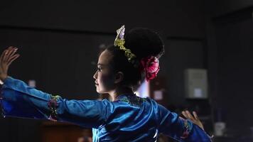 A dancer in traditional attire performs gracefully on stage, showcasing cultural heritage. The dancer's silhouette is highlighted against a dark background, emphasizing movement and elegance. video