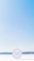 Minimalist White Clock on Pristine Snowy Landscape Under Clear Blue Sky A Serene Winter Timepiece Concept Image for Modern Design and Tranquility photo