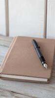 Elegant Fountain Pen and Textured Brown Notebook on a Light Wooden Surface, Perfect for Journaling, Creative Writing, and Thoughtful Reflection. photo