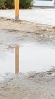Serene Puddle Reflection on Wet Ground with Wooden Post in Urban Landscape. Tranquil Outdoor Scene Capturing Natural Elements and Still Water. photo