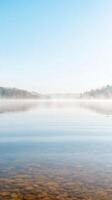 Tranquil Misty Lake at Dawn Serene Waters Reflecting a Clear Sky and Distant Autumn Hills photo