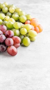 A captivating still life of vibrant green and ruby red grapes, artfully arranged on a textured white surface, evoking freshness and natural beauty for culinary visuals. photo