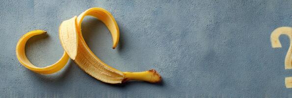 Curled Banana Peel Forms a Whimsical Question Mark Shape on a Smooth Surface photo