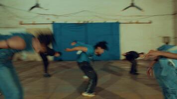Group of young dancers rehearsing in a studio with a blue backdrop, wearing casual outfits. video