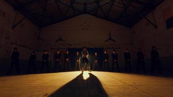 Silhouetted group watching a person with bright lights in a dark, atmospheric hall. video