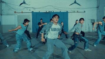 Group of young dancers in urban setting performing a routine with dynamic poses under hanging lights. video
