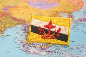 Eco themed photo of Brunei flag, embroidered with cloth and thread, positioned on a map at Brunei location. Great for topics on patriotism, travel, and climate awareness.
