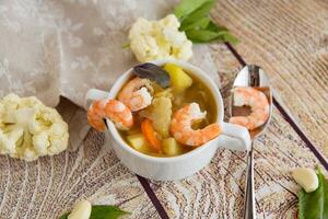 Culinary Serving of Hot Shrimp Soup on a Wooden Table photo
