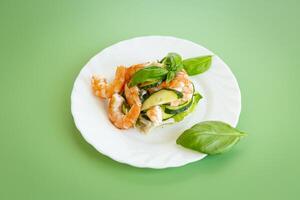 Fresh vegetable salad with shrimps and cucumbers on a green background . photo
