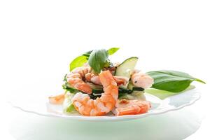 Fresh vegetable salad with shrimps and cucumbers on a white background photo