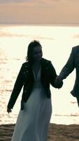 silhouette of two young people on a background of the sea. Young people walking on a background of sunset at sea. video