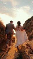 A young couple walks towards the sun between two mountains. Happy people holding hands and walking in front to the sun. Silhouette of a man and a woman on the video