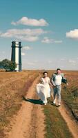 Two happy young people running together holding hands in a field. Lighthouse in the field. video