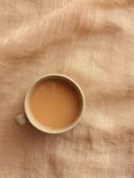 Warm beverage on textured linen fabric in soft caramel tone. Top view for cozy design photo