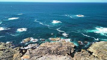 A stunning aerial view of a rocky coastline showcases ancient ruins alongside vibrant turquoise waves photo