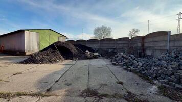 This storage site features large impressive piles of gravel and coal, enclosed by a sturdy fence under a clear blue sky photo