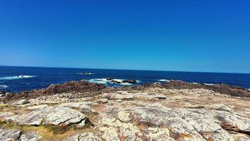 A stunning view shows a rugged coastline merging with a serene blue ocean under clear, beautiful skies photo