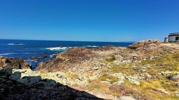 A breathtaking coastal landscape featuring rugged, jagged rocks alongside the shimmering blue ocean beneath a clear sky photo