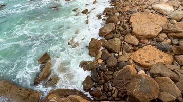 A breathtaking and stunning view of waves powerfully breaking against rugged rocks on a peaceful coastal shoreline photo