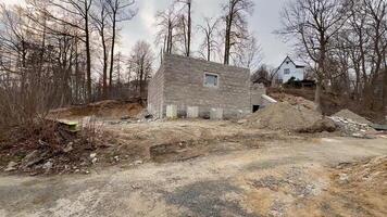An incomplete building is situated in a lush area surrounded by trees and scattered construction debris photo