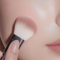 Applying pink blush with brush for youthful glow, perfect for skincare routine photo