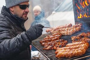 a man in a winter coat grilling meat on a grill photo