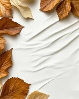 Autumn leaves scattered on textured white fabric background photo