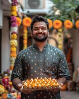 joyful man holds tray of lit lamps during festive celebration photo