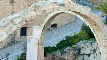 An old stone arch frames a picturesque cobblestone pathway surrounded by lush greenery, creating a breathtaking view video